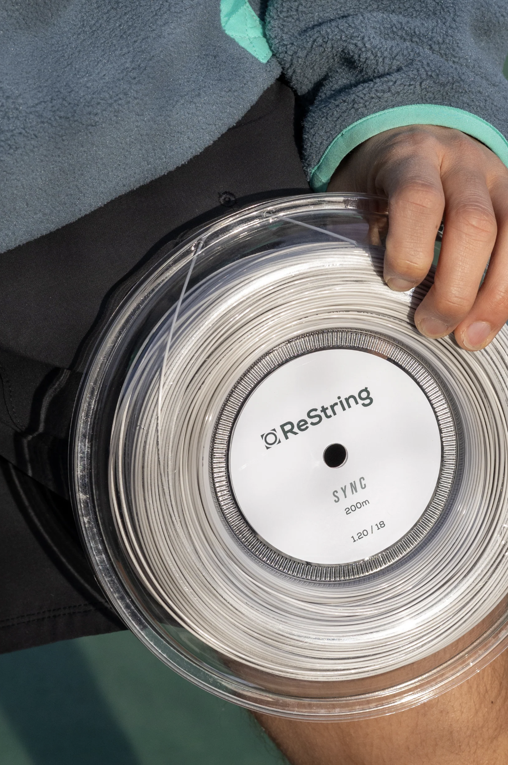 guy holding restring sync reel tennis strings